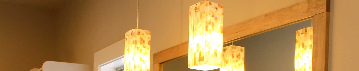 close up of artistic glass lighting hanging from ceiling in master bathroom