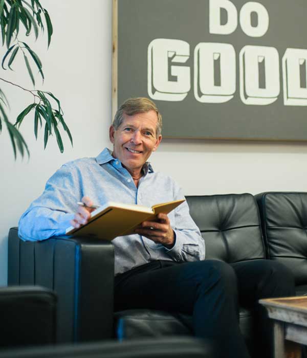 Chris Cipoletti sitting on black couch at the office entrance and reviewing meeting notes